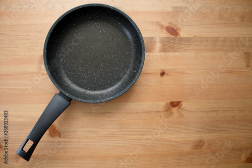 empty black pan on brown wooden background top view