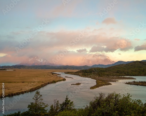 Pink colored sunrise over Torres del Paine mountains in Patagonia Chile. With river in foreground 