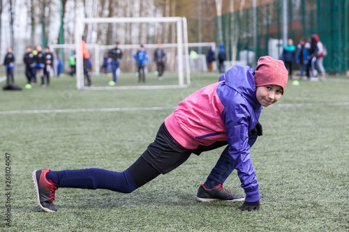Eleven-year female football player does exercises for flexibility, warm-up before a match
