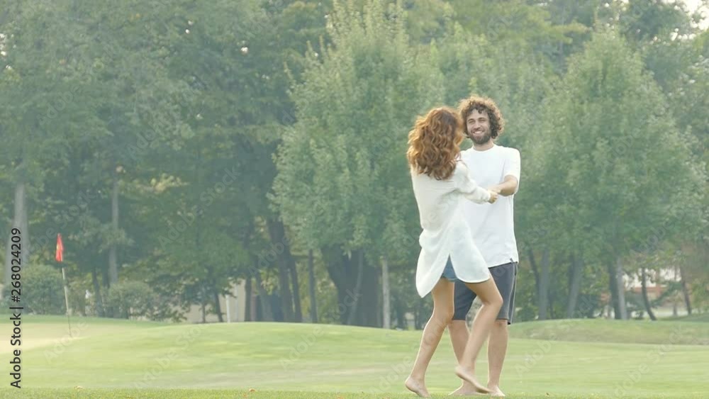 Happy couple in love enjoying nice summer day in the city park. Holding hands and whirl. Slowmotion. Happy couple in love enjoying nice summer day in the city park. Holding hands and whirl. Slowmotion.