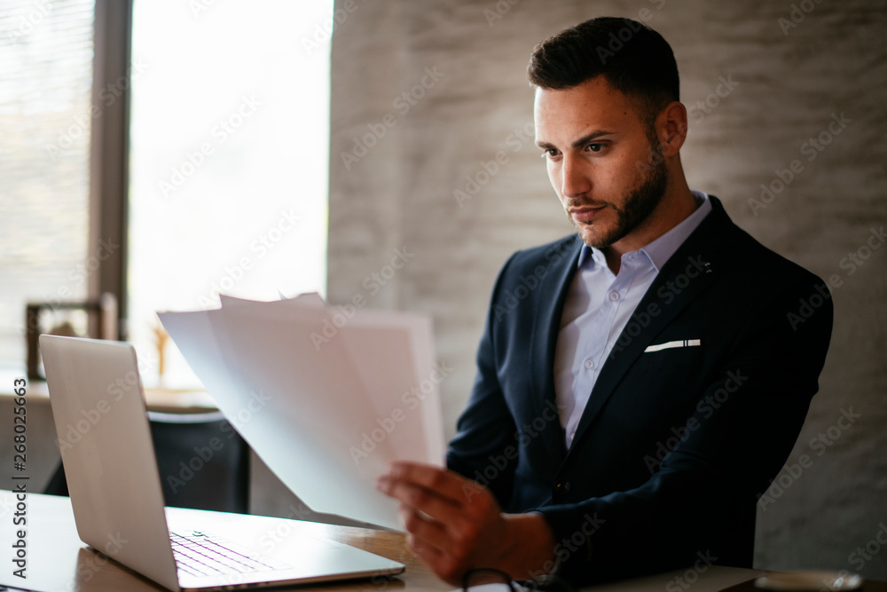 Attractive businessman doing paperwork in the office Attractive businessman doing paperwork in the office