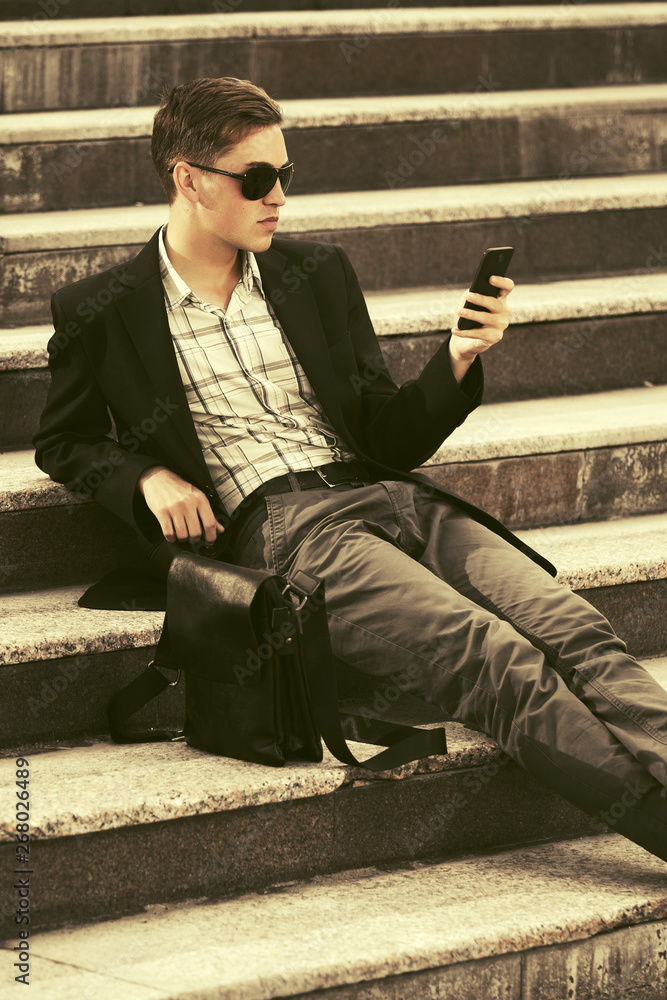 Young business man with cell phone sitting on steps