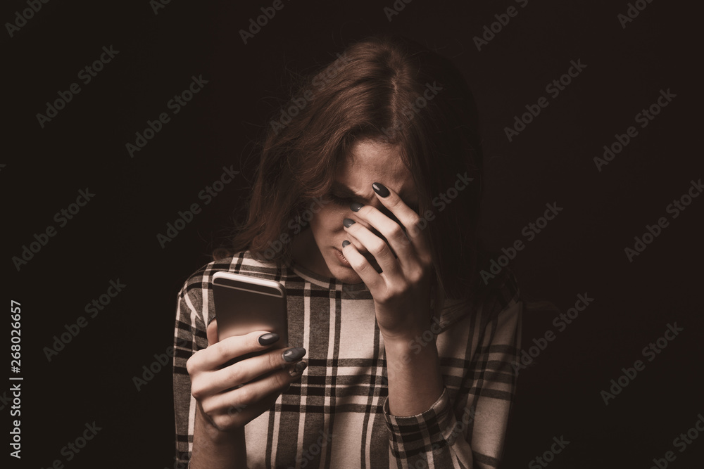 Φωτογραφία Sad teen being victim of cyber bullying online sitting on a couch in the living
