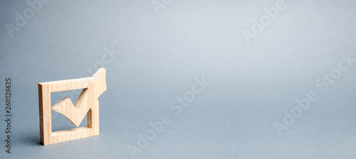 wooden checkmark for voting on elections on a gray background. Presidency or parliamentary elections, a referendum. Survey of the population, statistics, task. banner, place for text. Selective focus photo