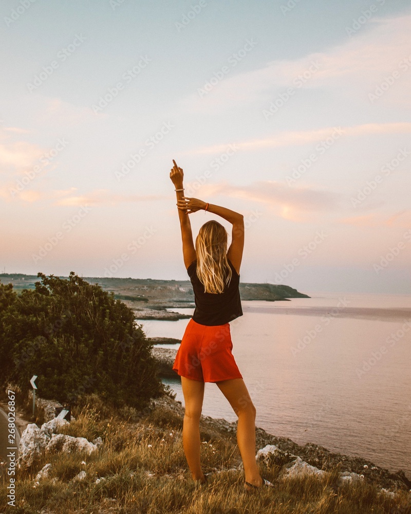 © Roberta Weislogel/Scopio - woman in black sleeveless top with red short shorts standing on hill near body of water © Roberta Weislogel/Scopio - woman in black sleeveless top with red short shorts standing on hill near body of water