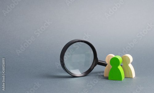 Konstfotografi Three wooden human figure stands near a magnifying glass on a gray background