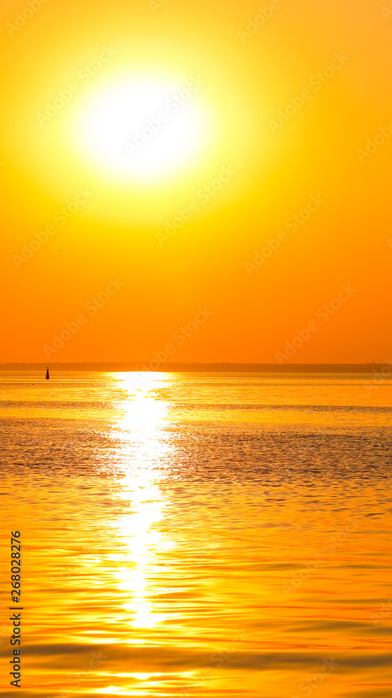 Orange sunset over the sea. Bright orange sun on horizon of the sea. Sunset in minimalism style in golden color. Holidays by the sea