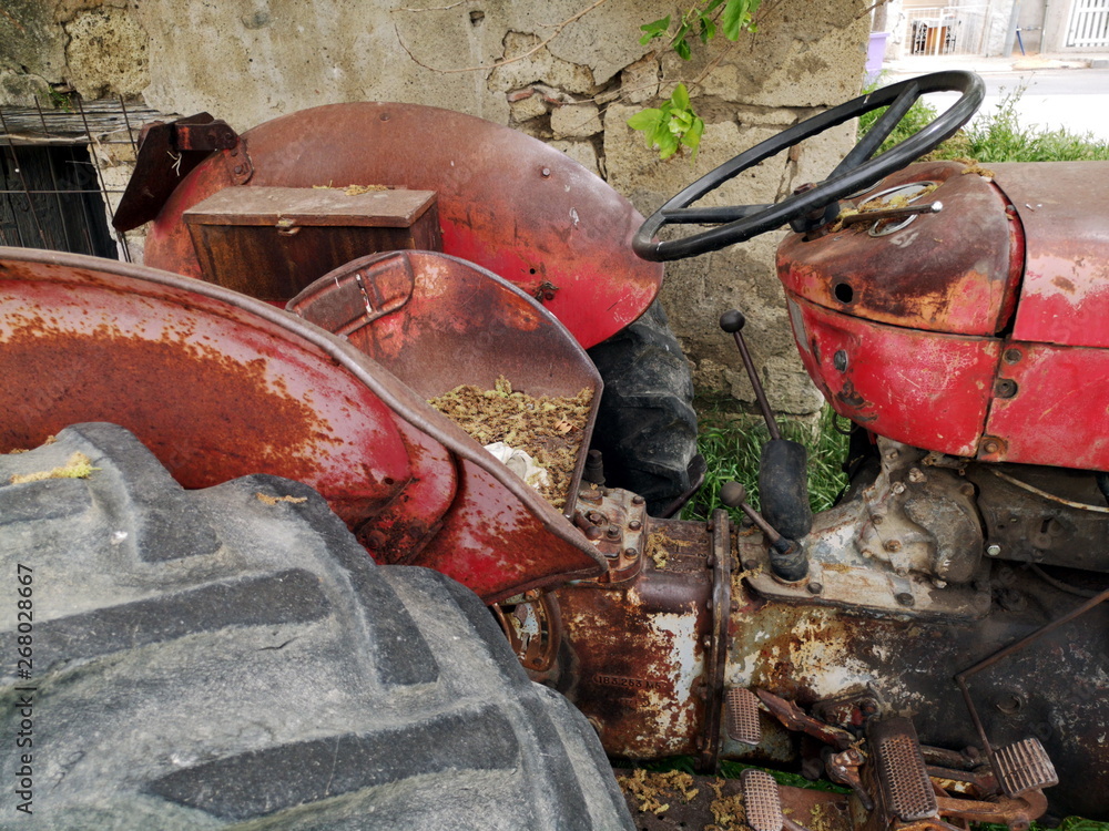 Φωτογραφία Lenkrad und Reifen eines ausrangierten Traktor in Rot für die Landwirtschaft mit