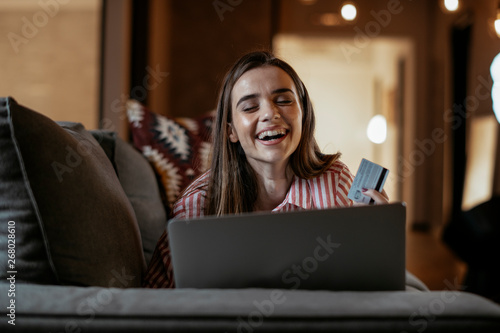 Young woman at home makes a purchase on the Internet on the laptop with credit card