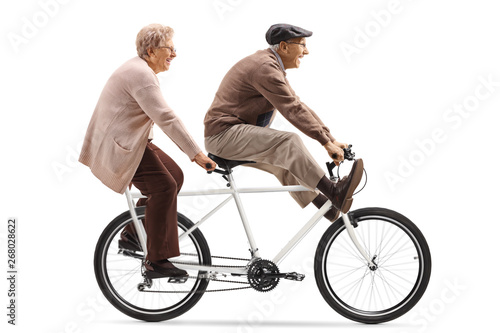 Senior man and woman riding a tandem bicycle with legs up