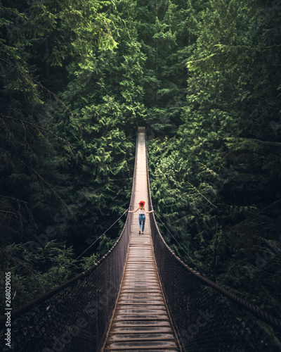 woman walking on hanging bridge at middle of forest photo