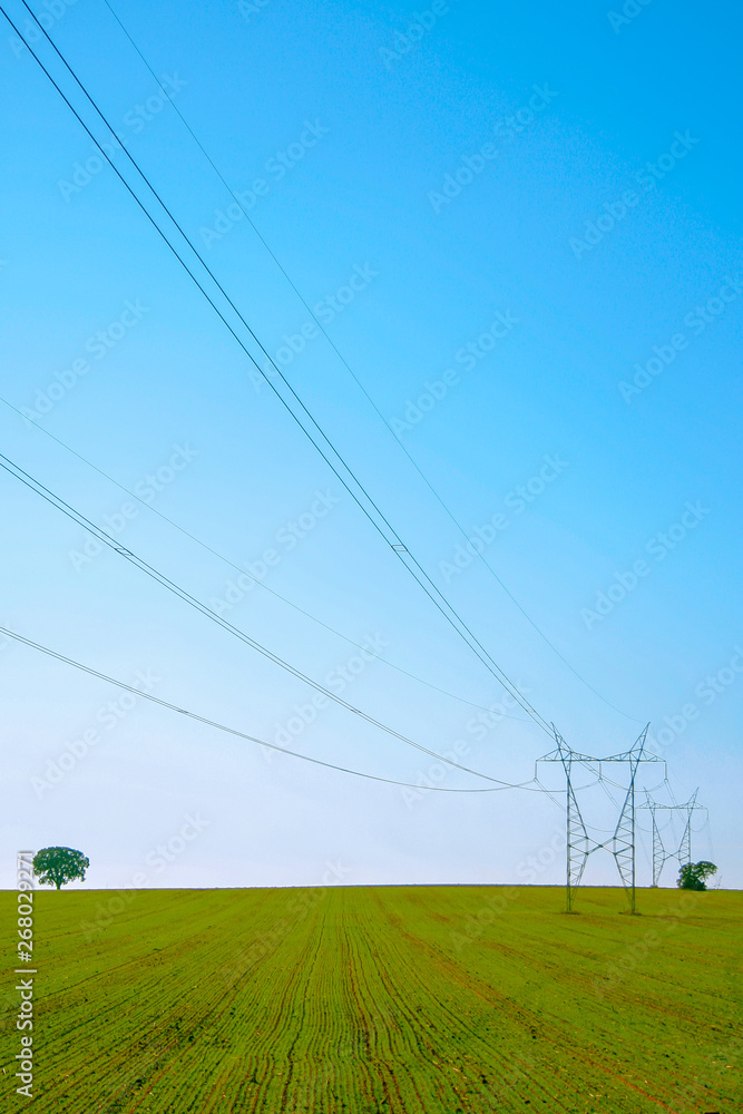 Electrical towers in a green field with blue sky Electrical towers in a green field with blue sky