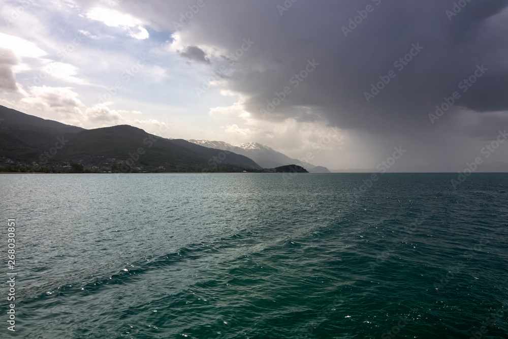 A thundering sky above Ohrid Lake with mountain hills on the horizon. Northern Macedonia. A thundering sky above Ohrid Lake with mountain hills on the horizon. Northern Macedonia.