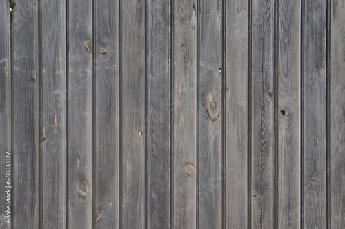 Vertically arranged gray shabby wooden planks. Old unpainted wooden wall - texture or background