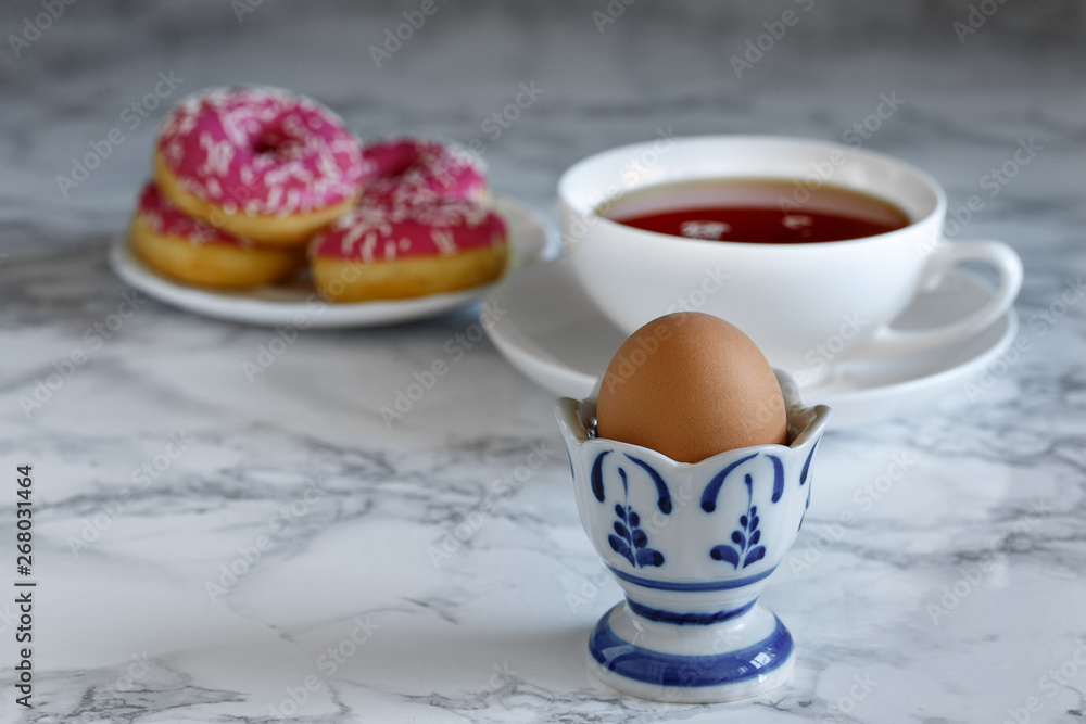 Boiled egg with tea and donuts in the background Boiled egg with tea and donuts in the background