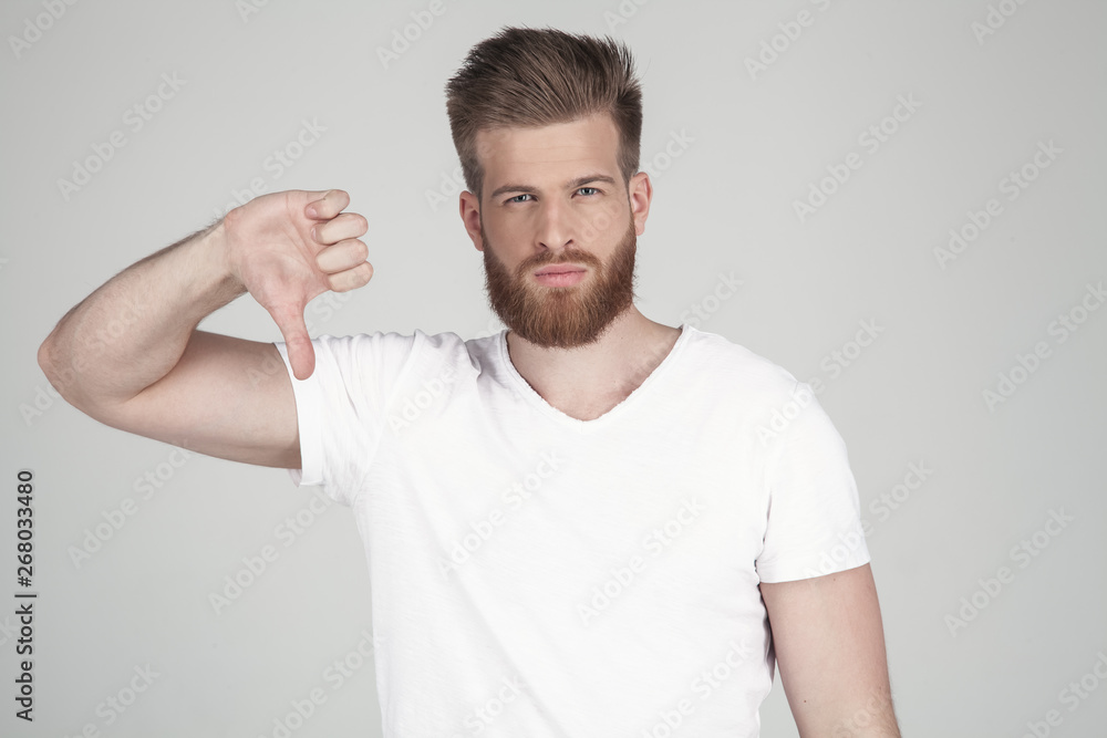 Portrait of a beautiful sexy bearded man. Shows a finger down. disapproves he stands in front of the white background Portrait of a beautiful sexy bearded man. Shows a finger down. disapproves he stands in front of the white background