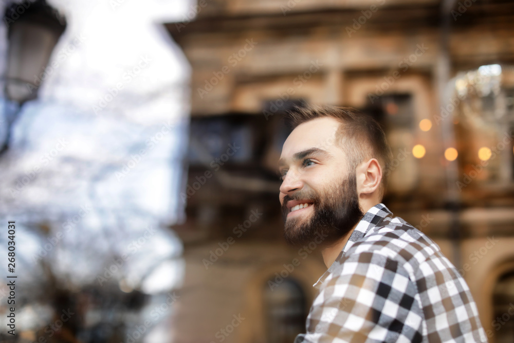 Handsome young man sitting in cafe, view from outdoors through window