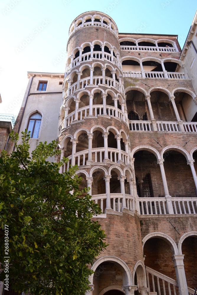Beautiful medieval tower with spiral staircase in Venice against the blue sky.