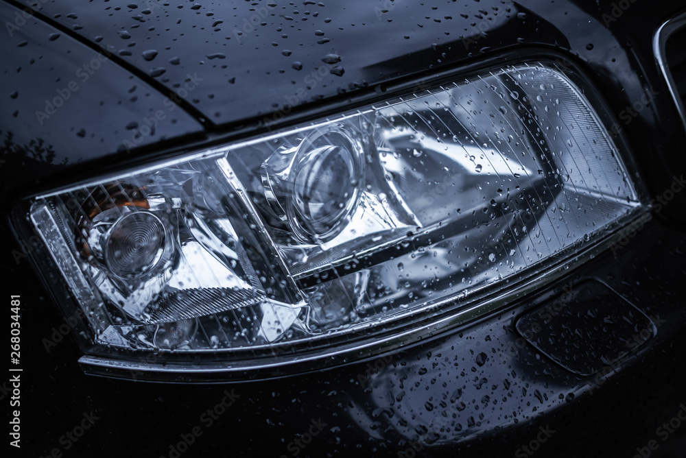 Car headlight. Wet car Headlamp close-up.