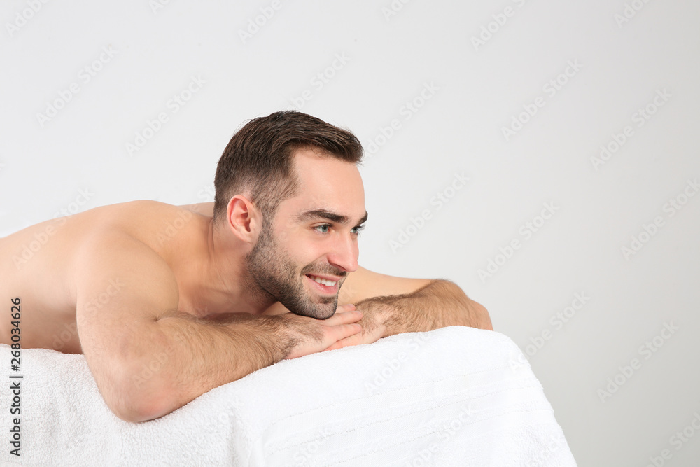 Obraz premium Handsome man relaxing on massage table against white background. Spa service