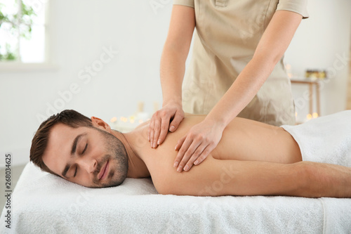 Handsome man receiving back massage in spa salon