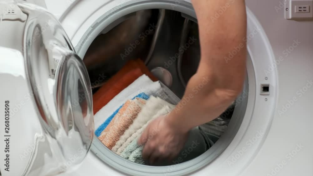 woman puts a stack of laundry in the washing machine and closes the door. Closeup. woman puts a stack of laundry in the washing machine and closes the door. Closeup.