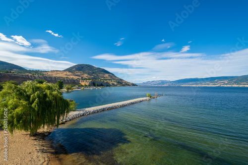 Magnificent view over Okanagan lake and valley with narrow foreland and clouds over blue sky