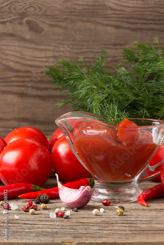 Fresh  tomato sauce and red tomatoes with dill, garlic, pepper on a wooden table.
