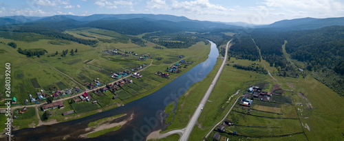 Aerial panorama of the river of Belaya with its green coasts with villages and Ural Mountains on the horizon photo