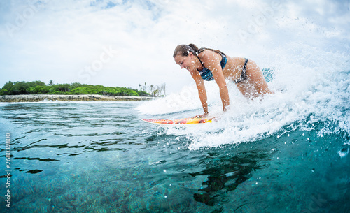 Happy young woman learns surfing in the tropics