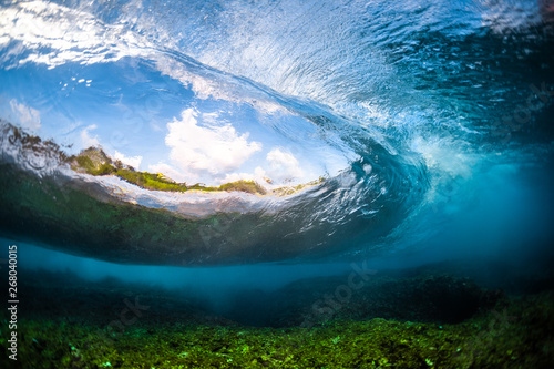 Ocean wave barrels and breaks over the shallow coral reef. Underwater view with the eye effect of the water