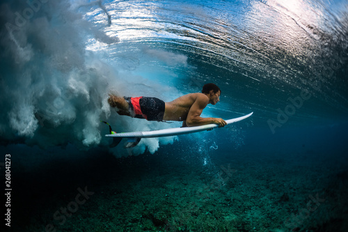 Surfer dives under the brea...