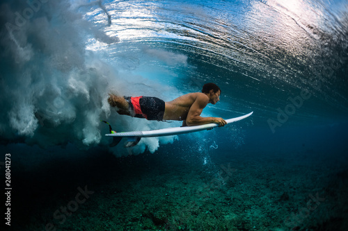 Surfer dives under the breaking wave in the tropics