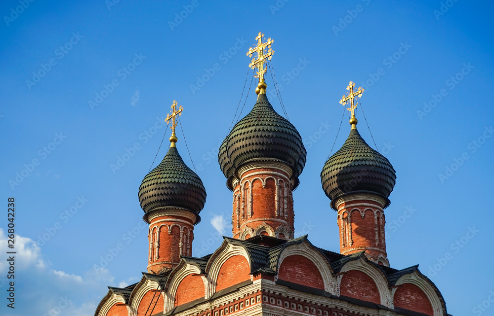 Domes of an Orthodox church, blue sky with clouds.