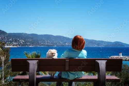 woman sitting with her pommeranian spitz puppy on a bench at the sea photo