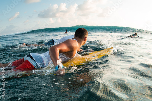 Photography Surfer paddle in the ocean and looks at the coming wave
