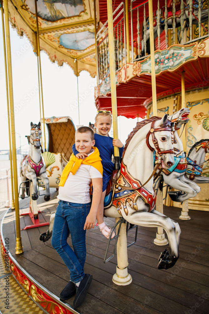 little children brother and sister having fun on the carousel little children brother and sister having fun on the carousel