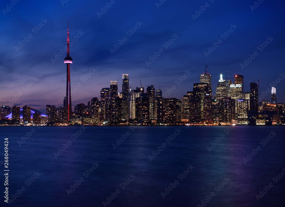 Twilight and Toronto city skyline with lights on highrise towers reflected Lake Ontario