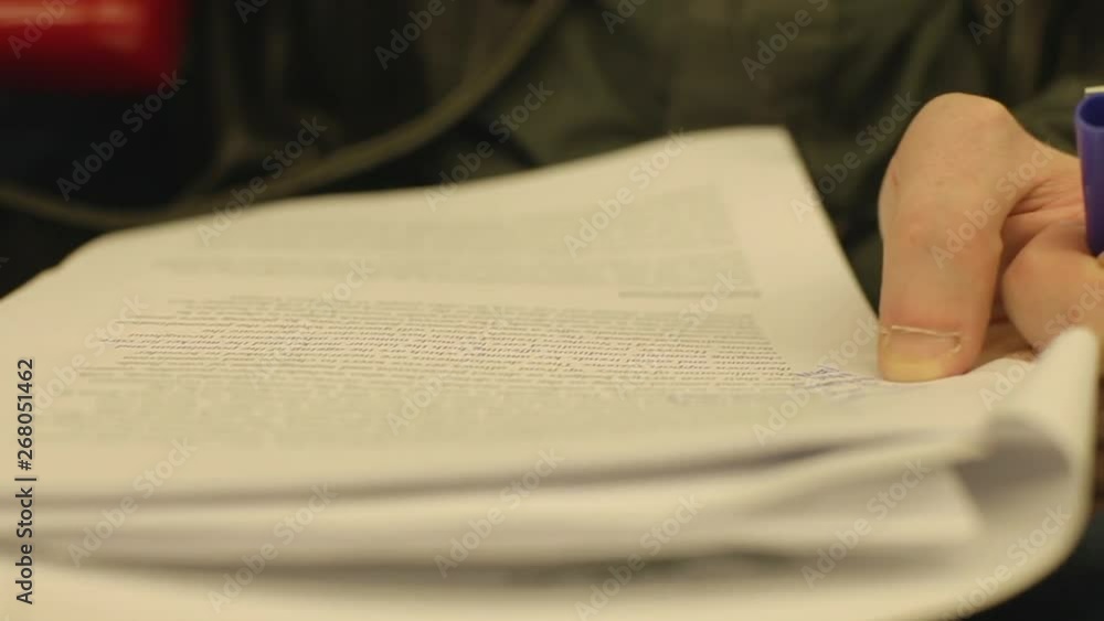 Handheld, close up shot of a person writing notes on a printed piece of paper. Handheld, close up shot of a person writing notes on a printed piece of paper.