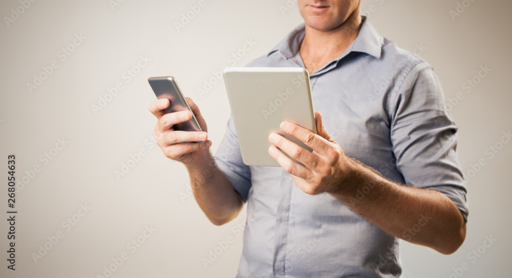 Man dressed casually in collared shirt using a tablet and phone - Casual business concept image with copy space for text. Man dressed casually in collared shirt using a tablet and phone - Casual business concept image with copy space for text.