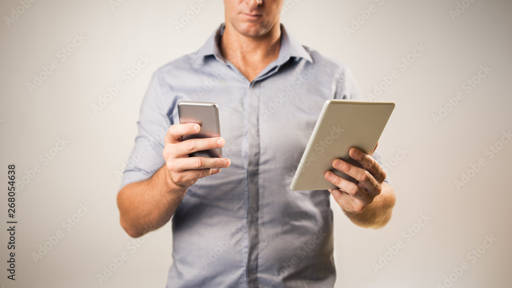 Man dressed casually in collared shirt using a tablet and phone - Casual business concept image with copy space for text. Man dressed casually in collared shirt using a tablet and phone - Casual business concept image with copy space for text.