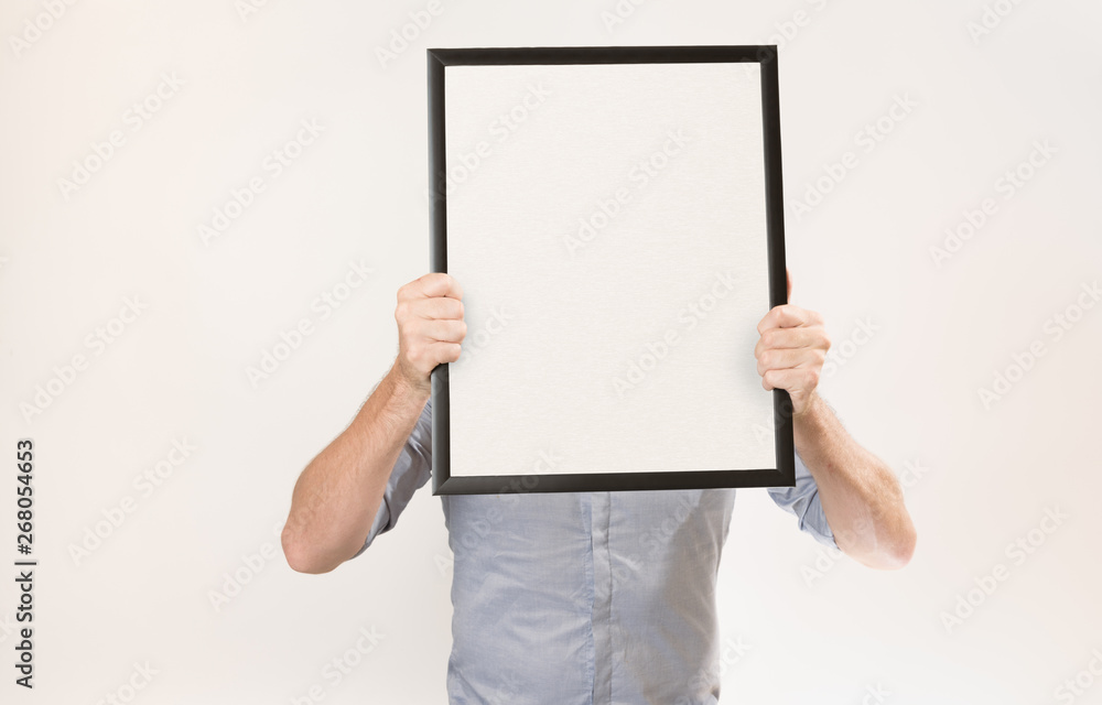 Unknown man wearing business shirt holding blank picture frame infront of his face Unknown man wearing business shirt holding blank picture frame infront of his face