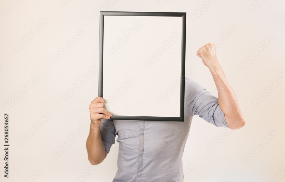 Unknown man wearing business shirt holding blank picture frame infront of his face Unknown man wearing business shirt holding blank picture frame infront of his face