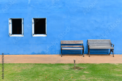 Two wooden chairs set in front of the blue plaster wall