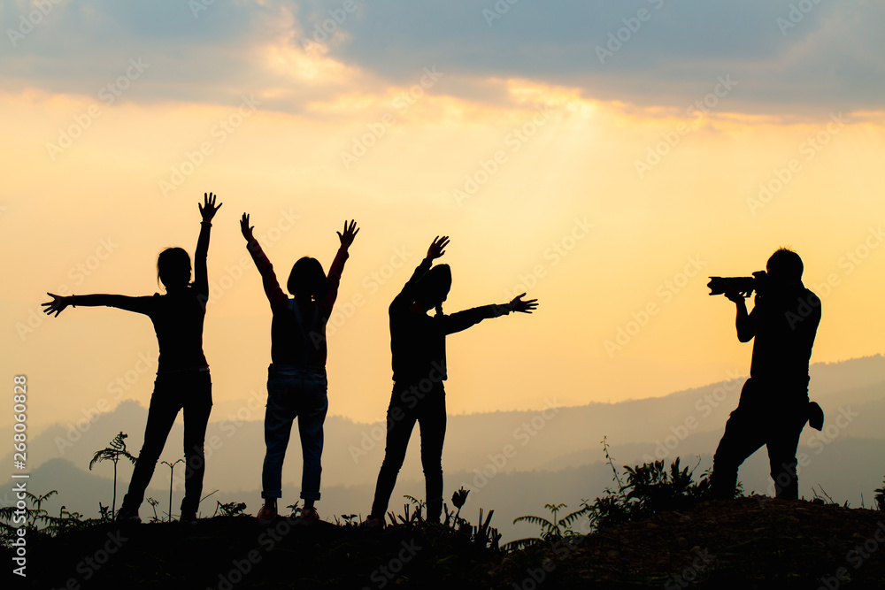 Silhouette of happy friends in sunset sky evening time background, Group of young people having fun on summer vacation, Youth lifestyle, party and friendship concept Silhouette of happy friends in sunset sky evening time background, Group of young people having fun on summer vacation, Youth lifestyle, party and friendship concept