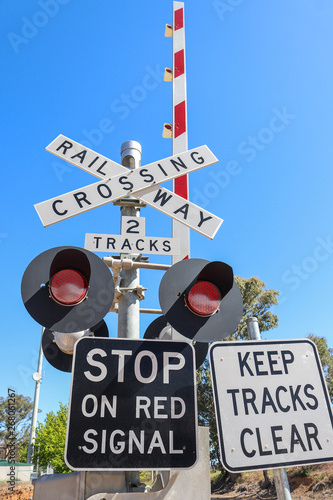 black, white and red railway crossing warning signs, lights and boom gates in a blue sky