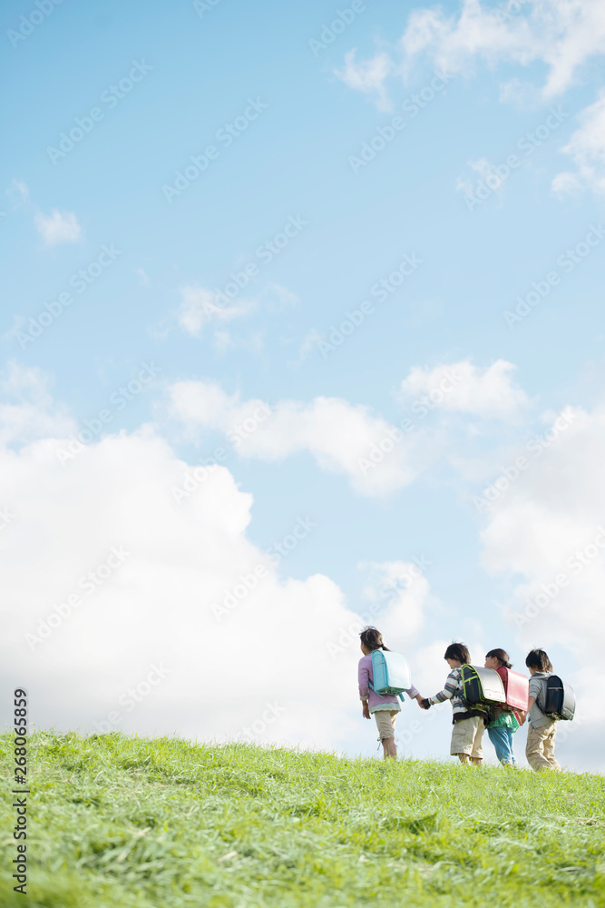 草原で手をつなぐ小学生の後姿