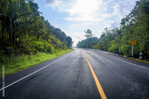 Asphalt road and mountains landscape under fog from rain with clouds © yotrakbutda