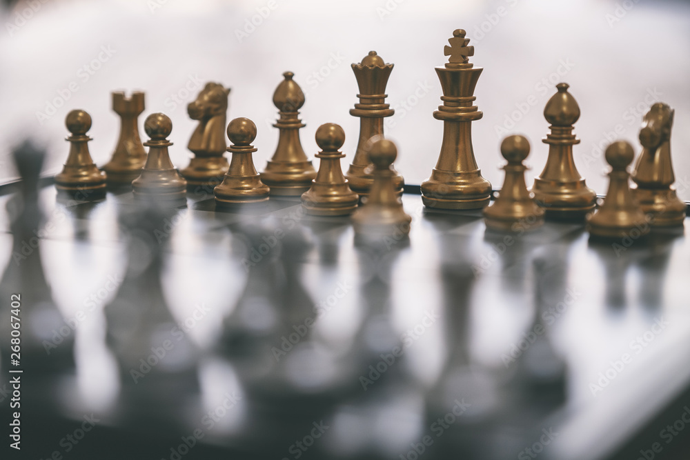 Closeup image of a silver and golden color chess set on chessboard Closeup image of a silver and golden color chess set on chessboard