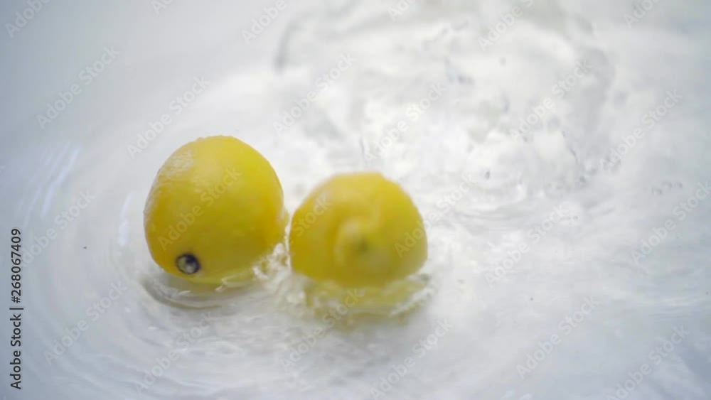 SLOMO of Lemons Falling into Water on White Backdrop SLOMO of Lemons Falling into Water on White Backdrop
